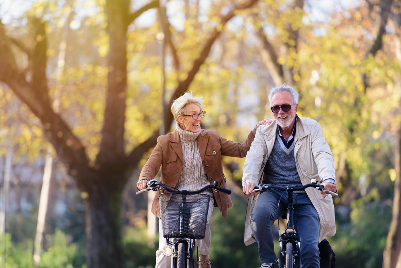 Fröhliches aktives Seniorenpaar mit Fahrrad im öffentlichen Park, das zusammen Spaß hat. Perfekte Aktivitäten für ältere Menschen. Glückliches reifes Paar fahren Fahrräder im Park