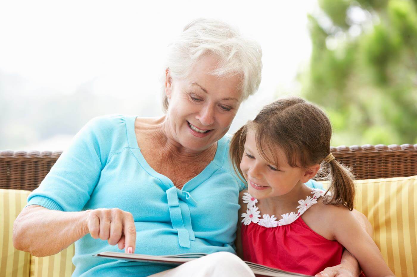 Großmutter und Enkelin lesen ein Buch auf einem Gartensitzplatz